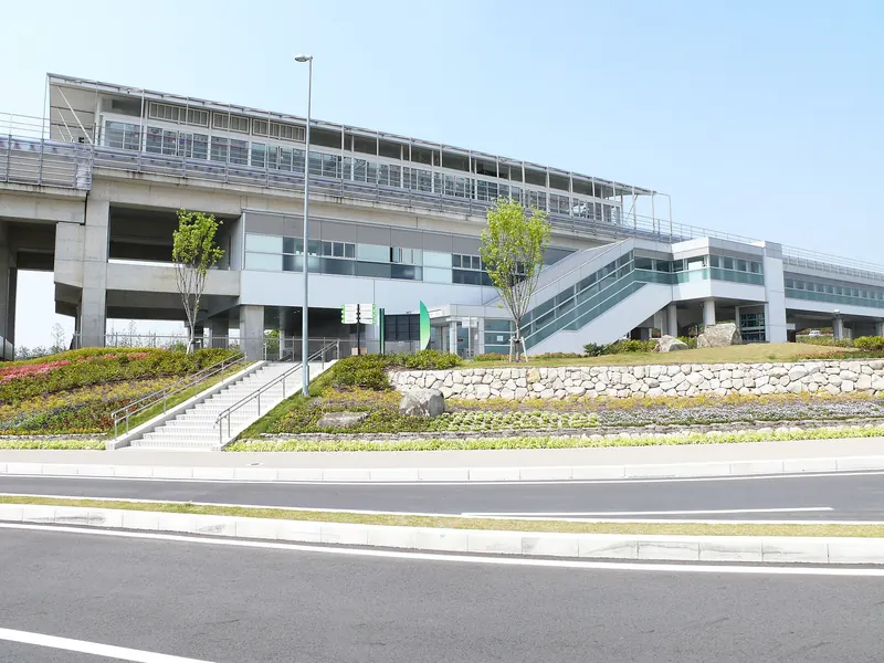 Ai-Chikyuhaku Kinen Koen Station on the Linimo line, an elevated station with stairs and planted banks beside the road
