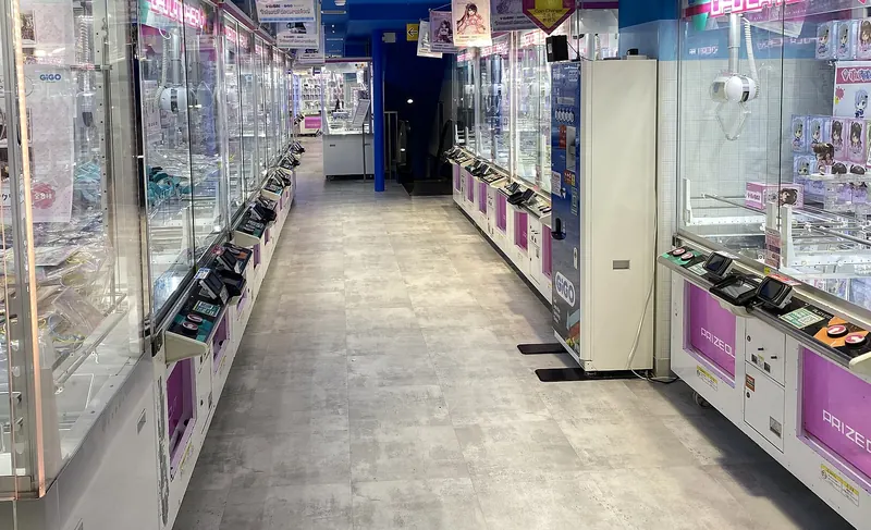 An empty aisle lined on both sides with glass-fronted claw machines in an arcade
