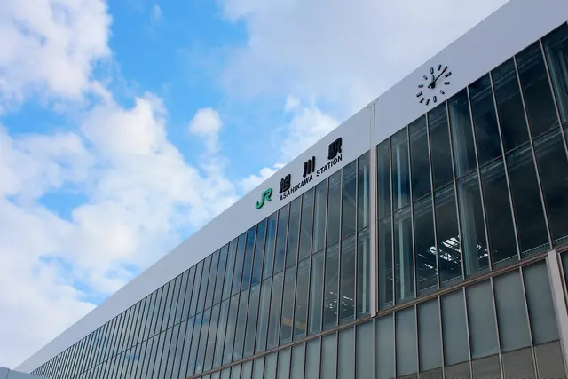 Glass front of Asahikawa Station with the station name in Japanese and English and a clock