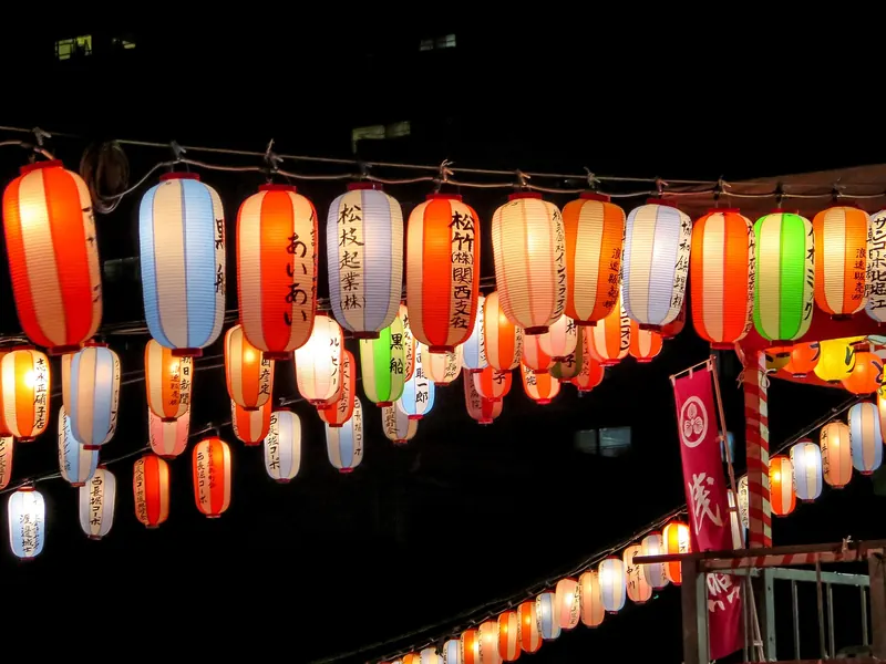 Strings of lit red, white, blue and green paper lanterns at night