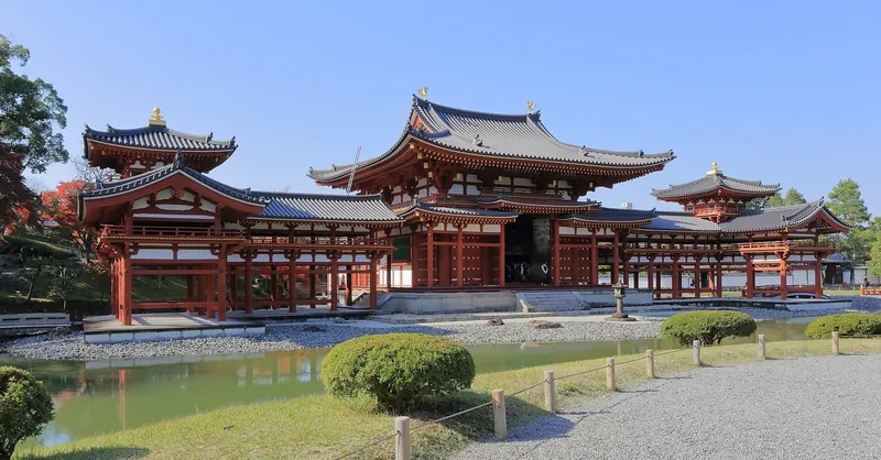 A red temple hall with two wings and a central roof reflected in a pond under a clear blue sky