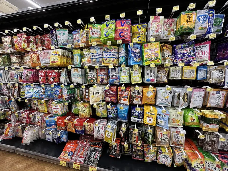 Rows of bagged sweets hanging on racks from top to bottom of a shop aisle