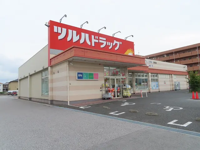 A drugstore with a large red sign and a car park