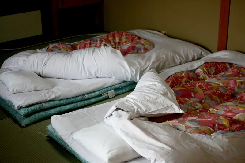 Two futons with patterned quilts laid out on tatami