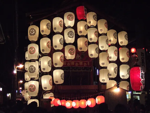 A festival float hung with rows of white paper lanterns at night