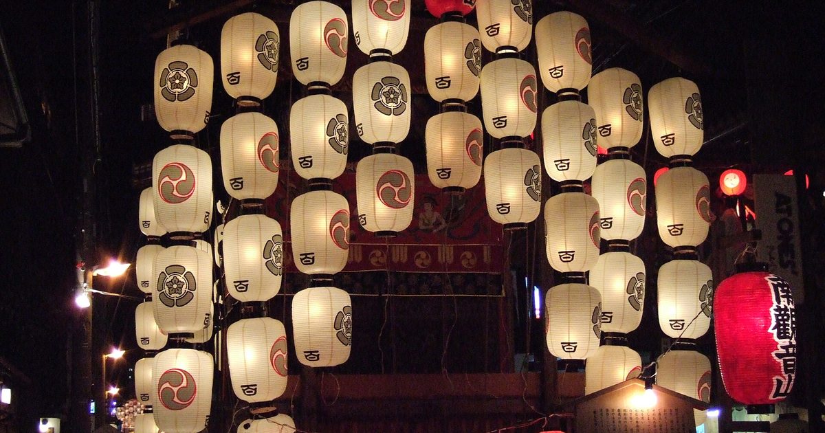 A festival float hung with rows of white paper lanterns at night