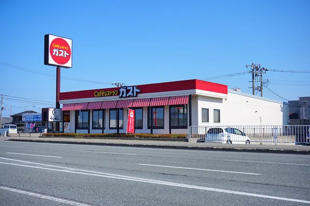 A low Gusto family restaurant with a red roof line beside a wide road