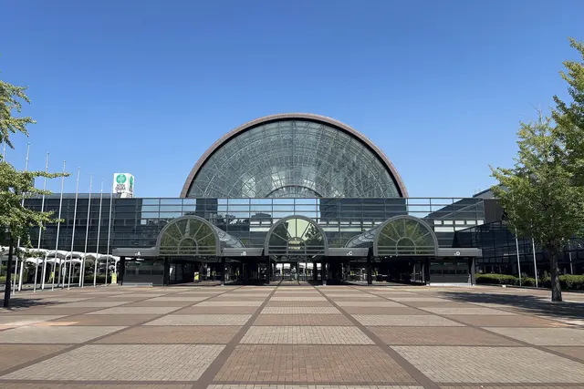 A brick-tiled plaza leading to an entrance with a glass barrel roof and three small arches