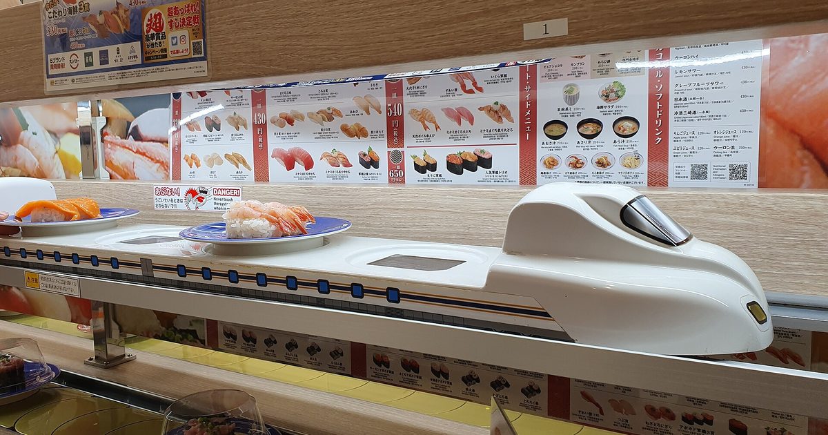 A Shinkansen-shaped delivery tray on the upper lane with plates on the conveyor below