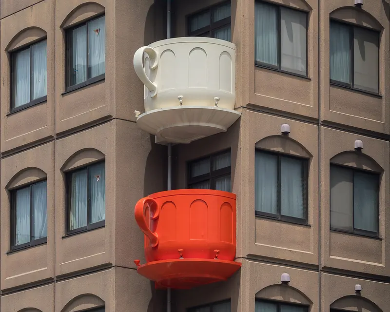 Two giant coffee cups, one cream and one red, fixed as balconies to the brown front of a building