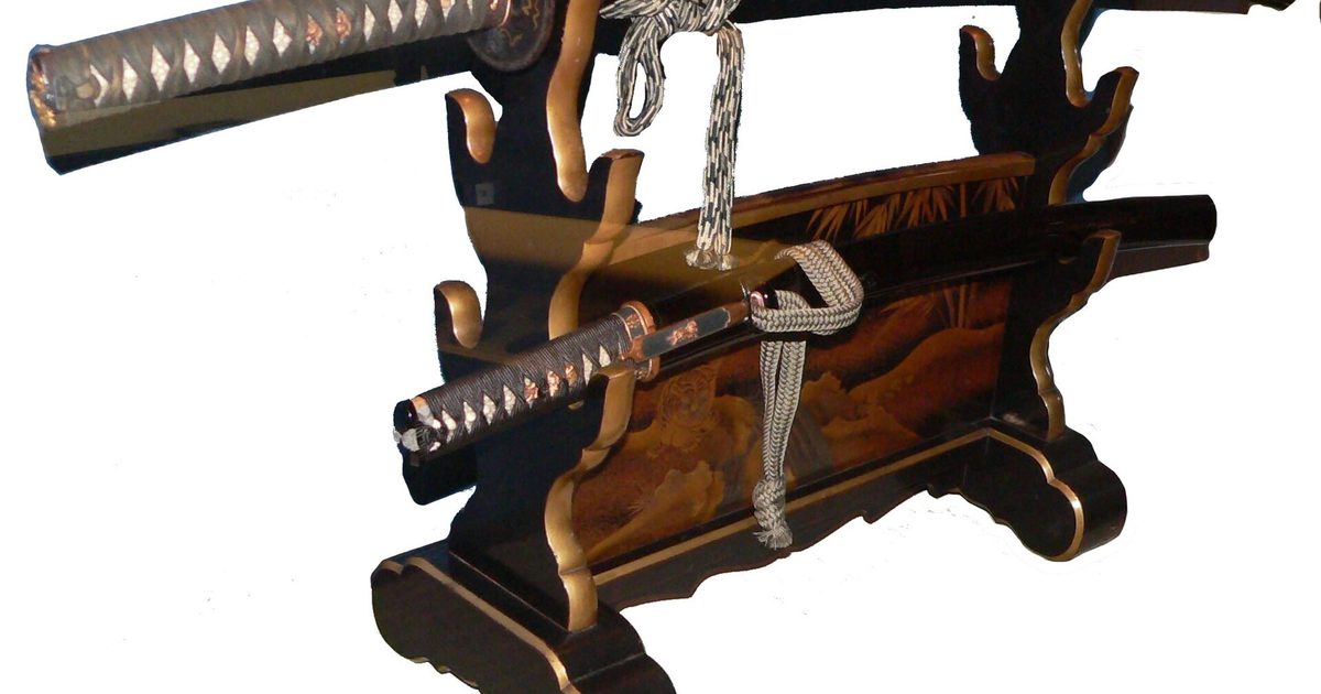 A long and a short Japanese sword in black lacquered scabbards resting on a horizontal lacquered sword stand