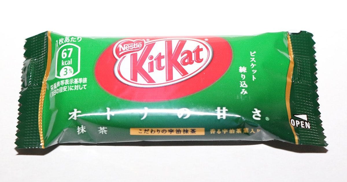 A mini Kit Kat in a green wrapper printed in Japanese, lying on a white background
