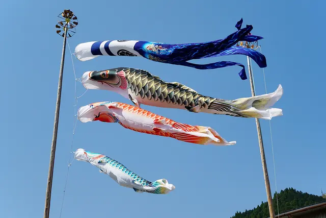 Four carp streamers flying from a pole against a blue sky