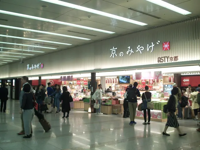A souvenir shop with the sign 京のみやげ in a station concourse with travellers walking past