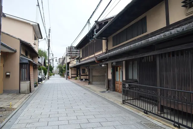 A quiet street lined with dark wooden townhouses in Kyoto