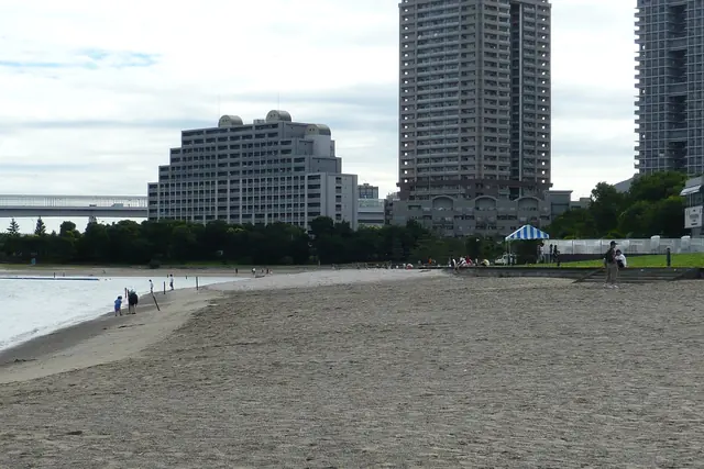 A sandy beach along calm water with tall buildings behind