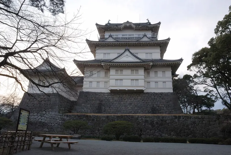 The white keep of Odawara Castle on high stone walls with bare trees