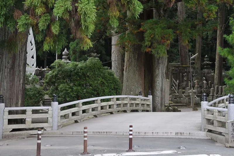 A granite bridge in front of old gravestones and tall cedar trees