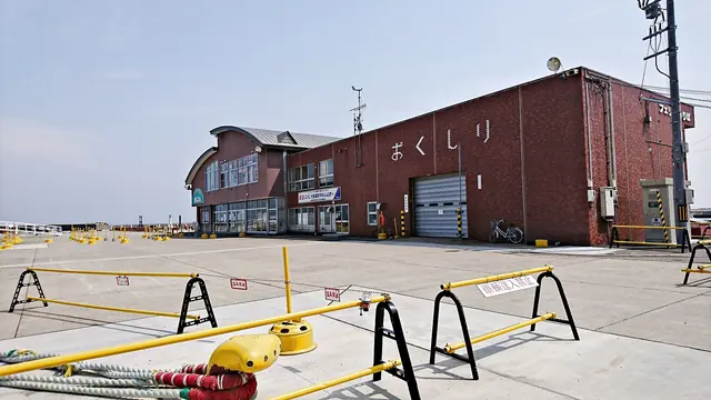 A long red-brick terminal building with the island's name in large Japanese letters on its wall and yellow barriers on the quay in front