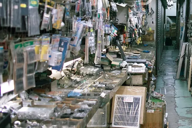 A stall crowded with trays of small electronic parts and bags of components hanging on racks, beside a narrow aisle