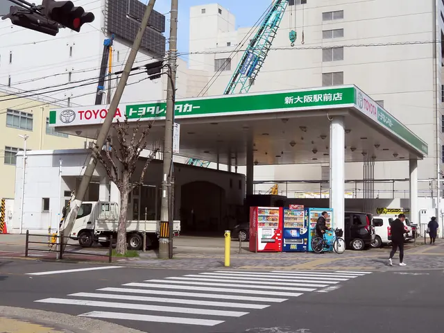 A car rental branch under a green-and-white canopy with a pedestrian crossing in front