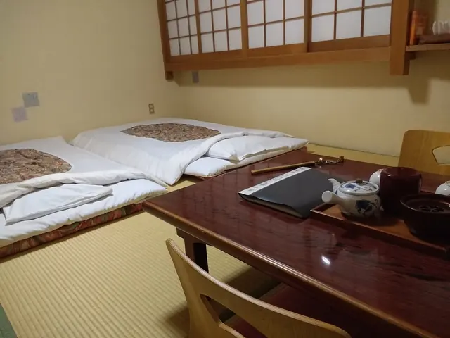 Photo: Mx. Granger (CC0) Two futons on tatami beside a low table with a teapot and a shoji window
