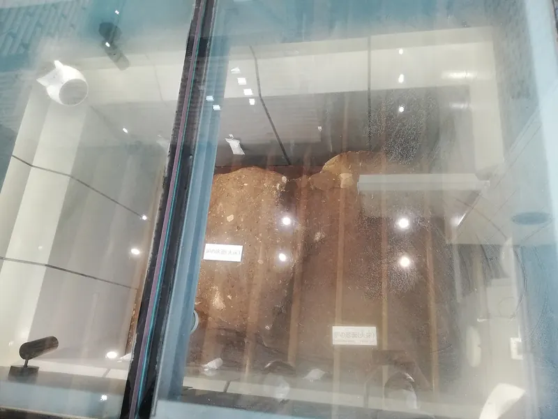 The remains of an old forge hearth seen from above through a glass cover, lit by small lamps