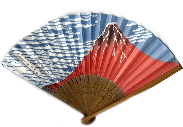 Photo: Tomomarusan (CC BY 2.5) An open folding fan with a red Mount Fuji and blue-and-white clouds on a white background