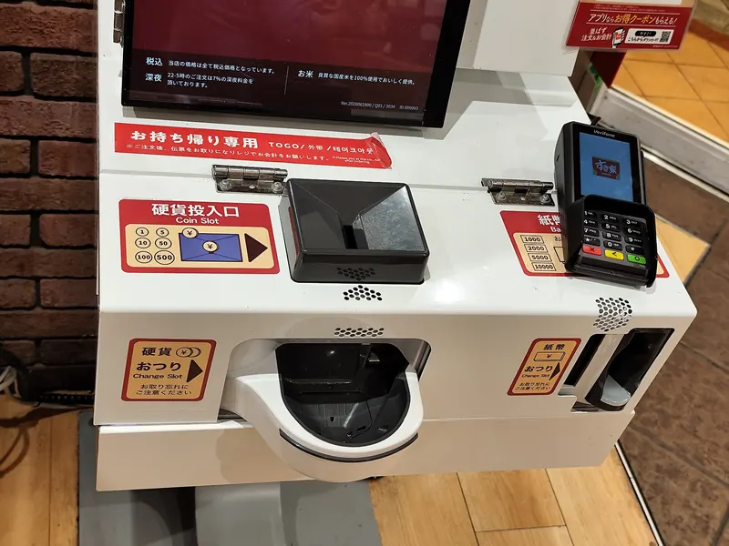 A white payment machine with a coin slot, a note slot and a card reader on top