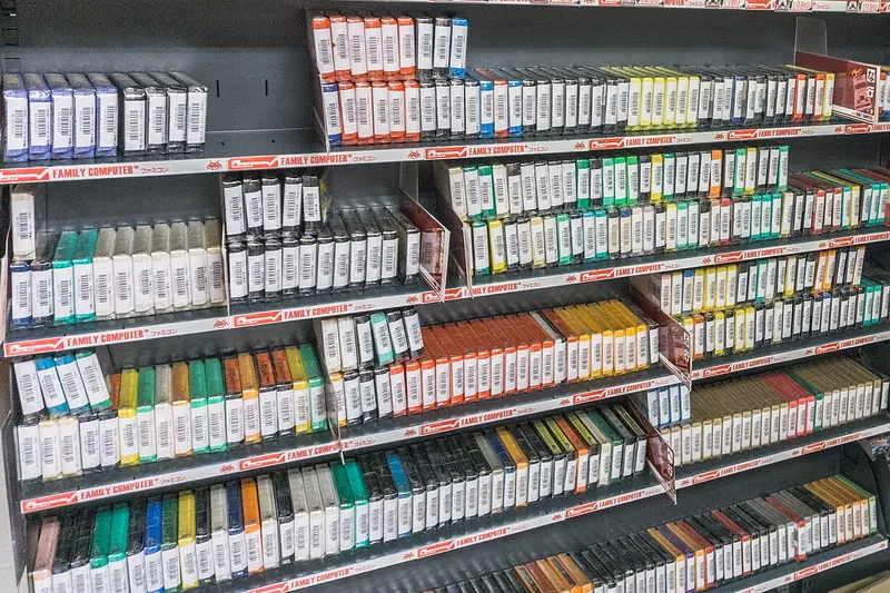 Shelves packed with rows of game cartridges in clear sleeves, spines out, with shelf labels reading FAMILY COMPUTER