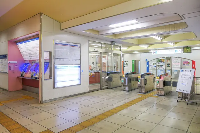 A station concourse with ticket gates on the right and fare machines on the left