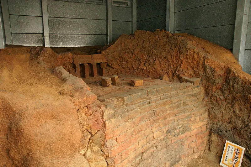 The red earth and brick remains of an old kiln under a shelter