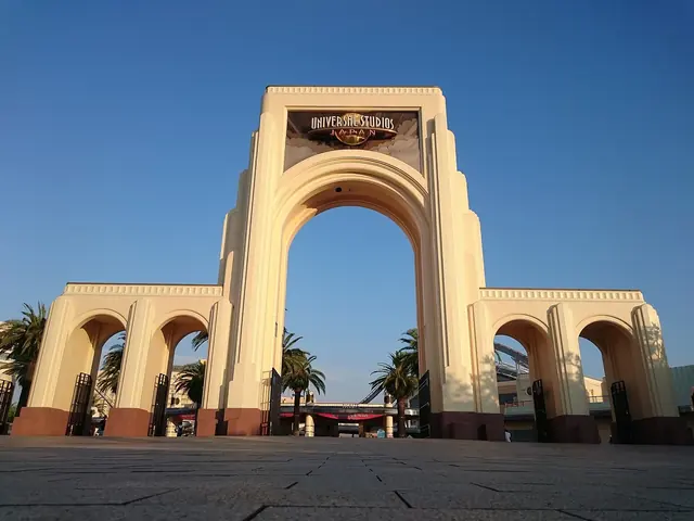 Photo: Rebirth10 (CC0) A large cream arch with Universal Studios lettering, flanked by palm trees under a blue sky