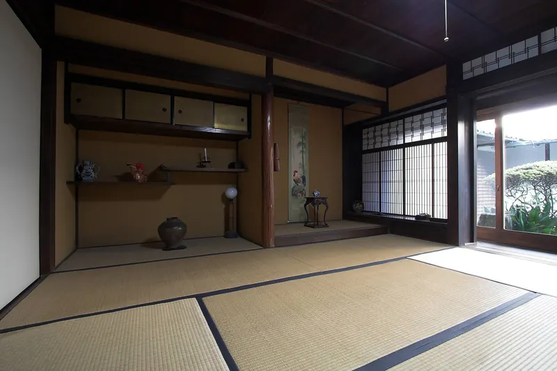 A tatami room with a tokonoma alcove, a hanging scroll, staggered shelves and shoji screens